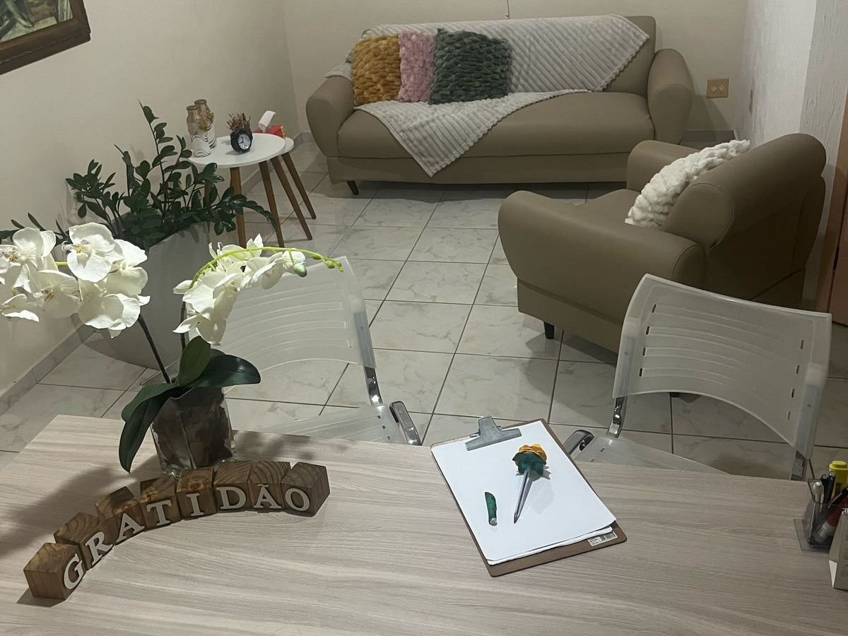 Mesa do consultório com orquídeas, uma prancheta e blocos de madeira escritos GRATIDÃO